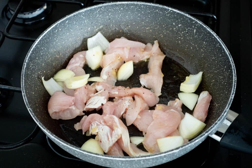 raw chicken and onions in a pan