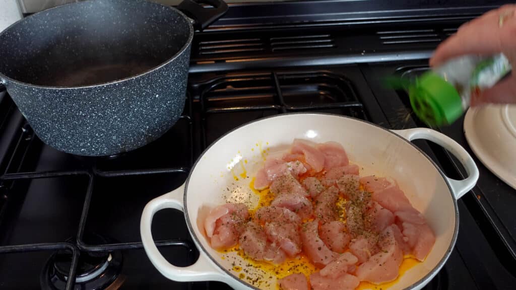 hot oil in pan with chicken and seasoning
