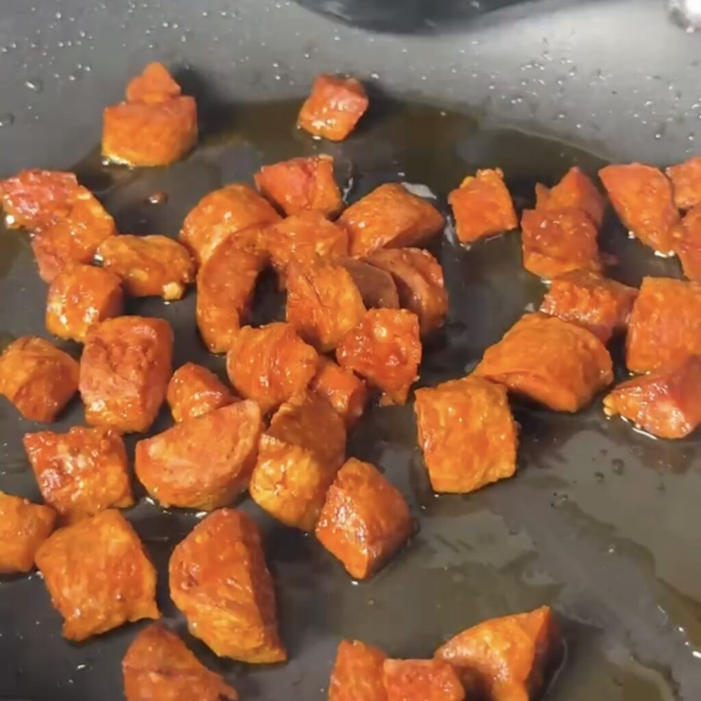 Diced chorizo frying in a pan until crispy
