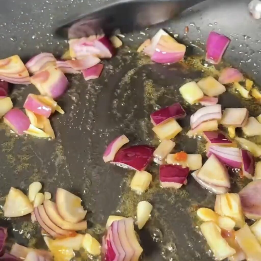 Diced red onion and garlic frying in chorizo oil in a pan
