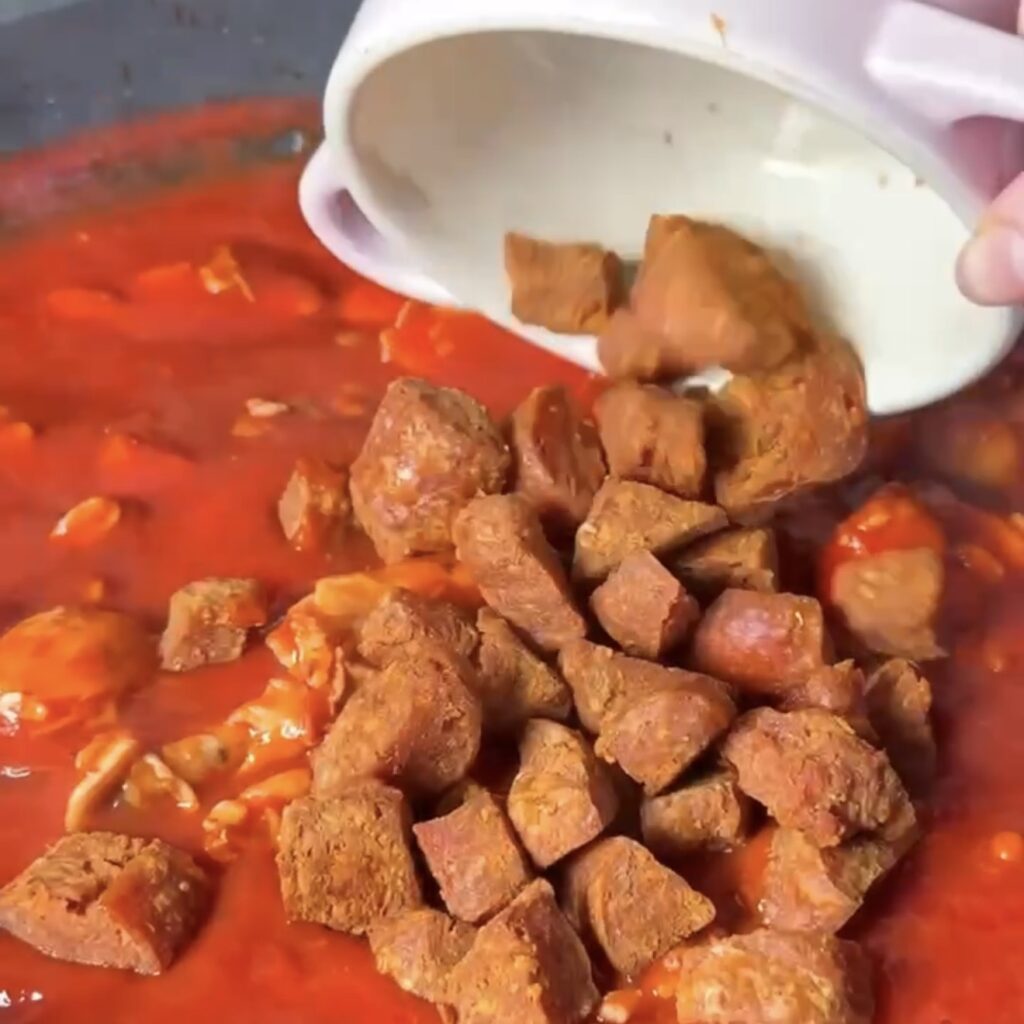 Crispy chorizo being added back into the tomato sauce with the chicken