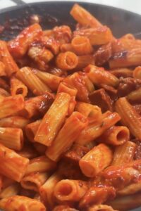 Finished chicken and chorizo pasta in a rich tomato sauce in a large pan